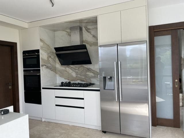 Witte maatwerkkeuken met marmeren achterwand, project van Mebo